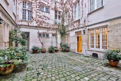un cortile di un antico edificio con piante in vaso di Charming 2 Bedroom Apartment in the Heart of Paris a Parigi