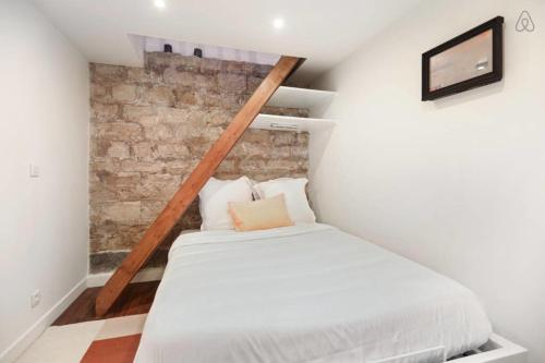 a small attic bedroom with a bed and a brick wall at Modern 1 Bedroom Apartment near Eiffel Tower in Paris