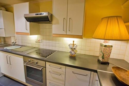 a kitchen with white cabinets and a lamp on a counter at Thistle Street Apartment at Heart of the City Centre in Edinburgh