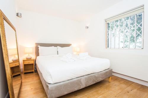 ロンドンにあるAmazing Spacious 1 Bedroom 15 Minutes to Central Londonの白いベッドルーム(大型ベッド1台、窓付)