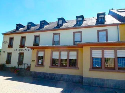 a large white building with windows and a roof at La Diligence in Arsdorf