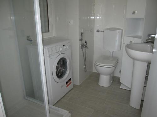 a bathroom with a washing machine and a toilet at Appartamento Pineta in Grado