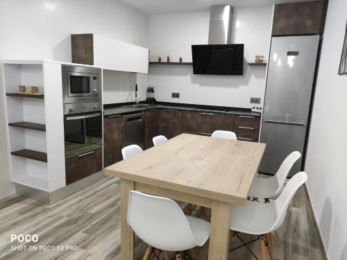 a kitchen with a wooden table and white chairs at Casa Rural Lavernia in Cabanes
