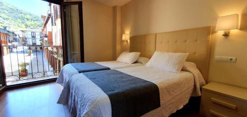 a bedroom with a bed and a large window at Hotel Molina Real in Molinaseca