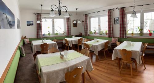 un restaurante con mesas y sillas blancas y ventanas en Haslehnerhof, en Ramsau am Dachstein