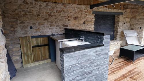 baño con lavabo y pared de piedra en Gîtelabaronnaise avec piscine chauffée prés parc Asterix, en Baron