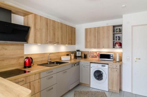 a kitchen with wooden cabinets and a washer and dryer at Ferienparadies Bodensee Fewo2 in Billafingen