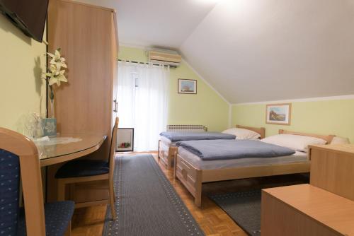 1 dormitorio con 2 camas, mesa y escritorio en Guest House Bagi, en Požega