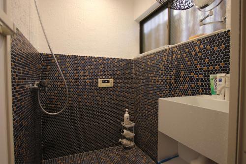 a bathroom with a shower and a toilet and a sink at May Guest House in Tokyo