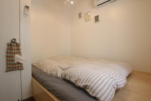 May Guest House في طوكيو: سرير في زاوية من الغرفة