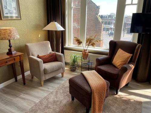 a living room with two chairs and a table and windows at Hotel restaurant Stad Munster in Winterswijk