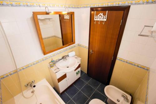 a bathroom with a sink and a toilet and a mirror at Casa da Torre com garagem gratuito in Aveiro