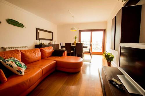 a living room with an orange couch and a dining room at Casa da Torre com garagem gratuito in Aveiro