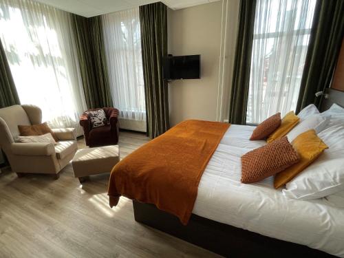 a hotel room with a bed and a chair and windows at Hotel restaurant Stad Munster in Winterswijk