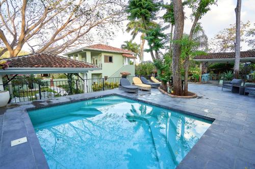 una piscina con 2 sillas y una casa en Hotel Casa Leona, en Tamarindo