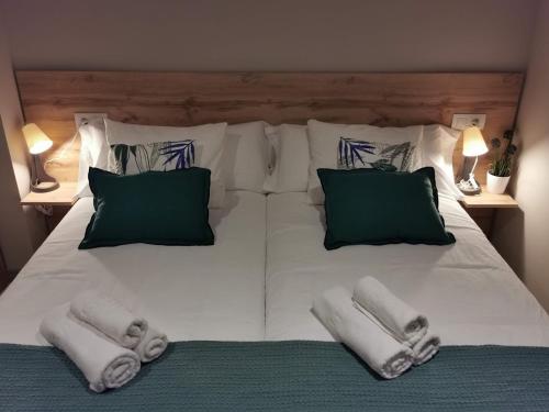ein großes weißes Bett mit Kissen und Handtüchern darauf in der Unterkunft Km101 in Baamonde
