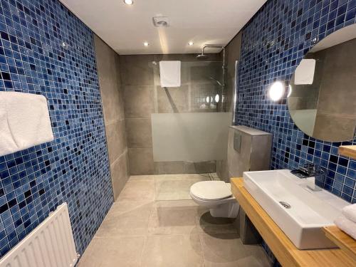 Baño de azulejos azules con aseo y lavamanos en Hotel restaurant Stad Munster, en Winterswijk
