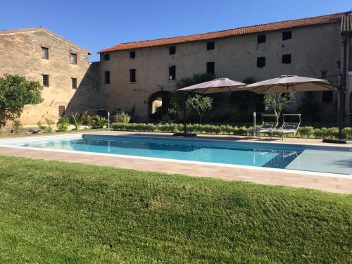 uma piscina com guarda-sol e cadeiras e um edifício em DIMORA DESENZANI - Lago di Garda em Esenta