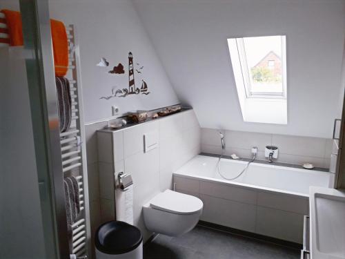 a bathroom with a toilet and a tub and a window at Ferienwohnung Am Damm in Wesel