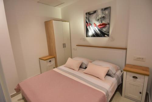 Un dormitorio con una cama y un cuadro en la pared. en Villa NEDE, en Podgora