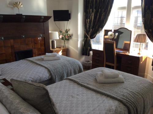 a bedroom with two beds and a desk and a mirror at The Gables in Hunstanton