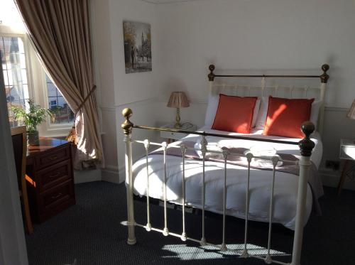 a bedroom with a bed with red pillows and a window at The Gables in Hunstanton