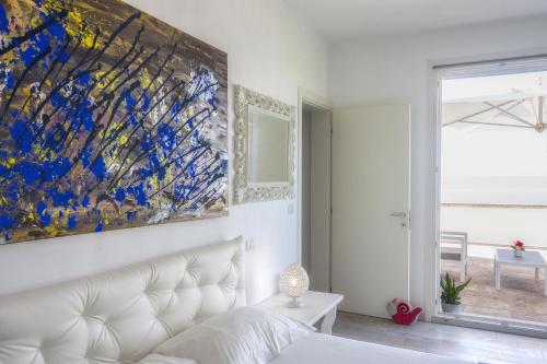 a white bedroom with a large painting above a bed at Suite Jonica in Torre Suda