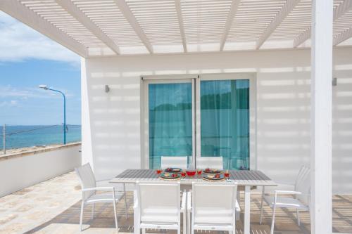 a table and chairs on a patio with the ocean at Suite Jonica in Torre Suda