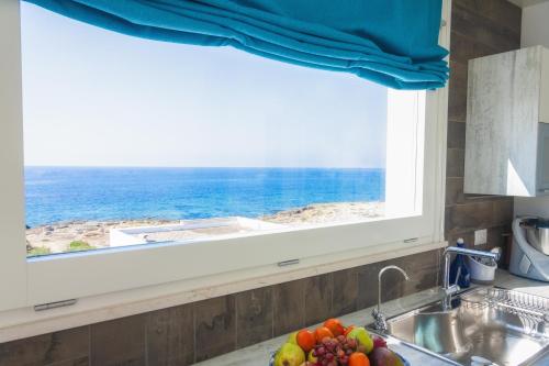 a kitchen sink with a window and a bowl of fruit at Suite Jonica in Torre Suda