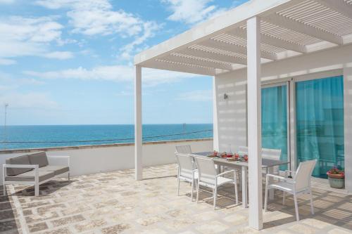 a patio with a table and chairs and the ocean at Suite Jonica in Torre Suda