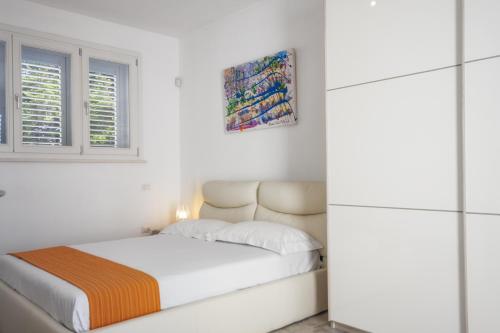 a white bedroom with a bed and a window at Suite Jonica in Torre Suda