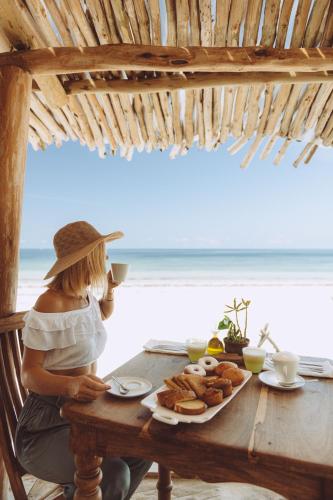 uma mulher sentada à mesa com um prato de comida em Mvuvi Boutique Resort em Kiwengwa