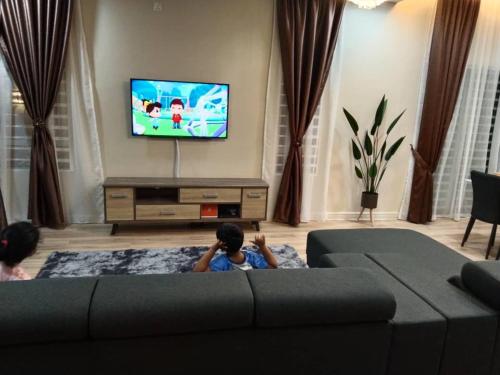 two children sitting on a couch in a living room at Villa with private Pool and Sauna @ Nilai in Nilai