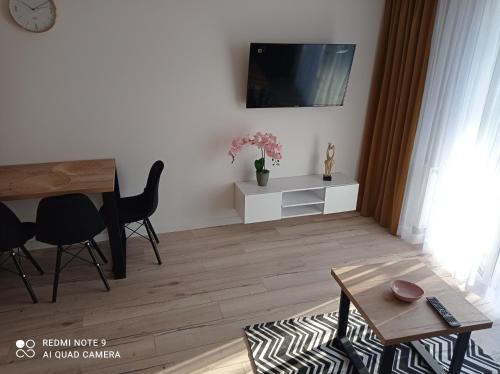 a living room with a table and a tv on a wall at Apartament Mazury Węgorzewo in Węgorzewo