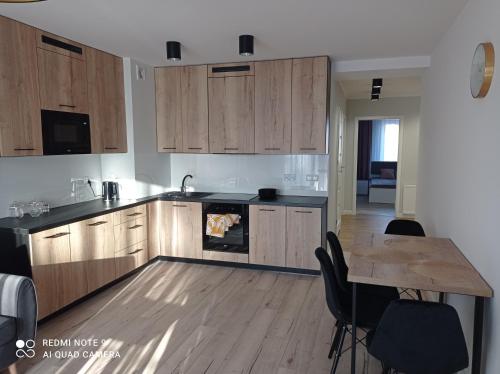 ベンゴジェボにあるApartament Mazury Węgorzewoのキッチン(木製キャビネット、テーブル付)、ダイニングルームが備わります。