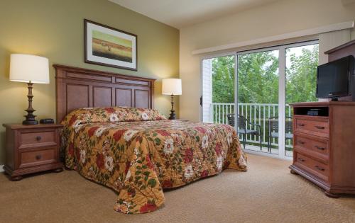 a bedroom with a bed and a television and a balcony at WorldMark Lake of the Ozarks in Osage Beach