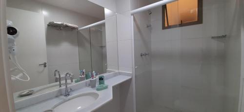 a white bathroom with a sink and a shower at Loft Sahy - Condado Aldeia dos Reis in Mangaratiba