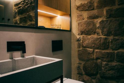 La salle de bains est pourvue d'une baignoire et d'un mur en pierre. dans l'établissement Casa Boutique Nº24, à Cardona