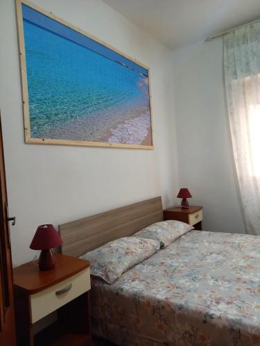 a bedroom with a bed and two tables and a picture on the wall at baia verde appartamento 150 m dal mare in Gallipoli