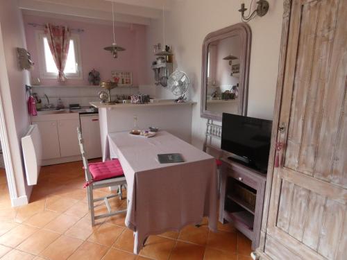 a small kitchen with a table and a television at Les Petits Matins Bleus - Chambres d'hôtes "Les Pommiers" in Sainte-Marguerite-de-Viette