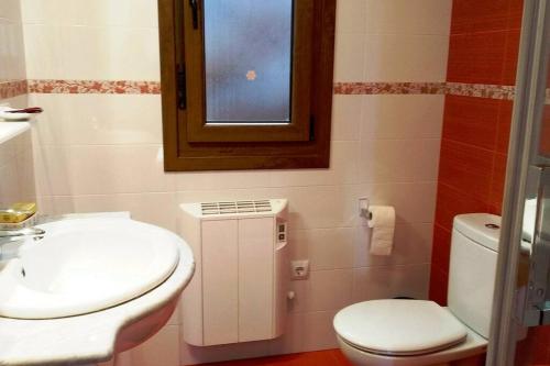uma casa de banho com um WC, um lavatório e uma janela em El Mirador de Cobeña II. Aires de Liébana en Picos em Cobeña