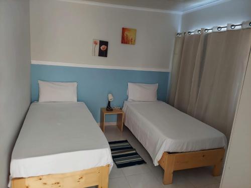 2 łóżka w małym pokoju z niebieskimi ścianami w obiekcie IMOBITUR-Tourist Apartments- Palmarejo Centro AV SV w mieście Praia