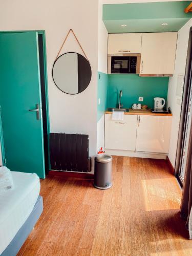 a room with a kitchen with a green door and a table at Le Clos Vernay in Nivolas-Vermelle