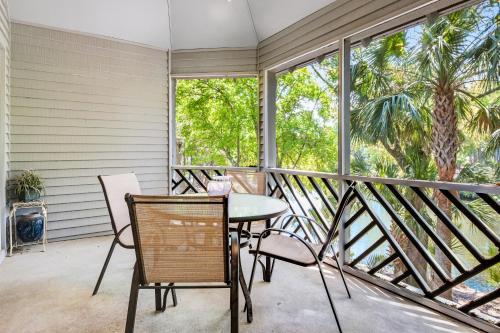 einen Balkon mit einem Tisch, Stühlen und Fenstern in der Unterkunft Turtle Cove 5552 in Kiawah Island