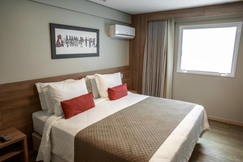 een hotelkamer met een groot bed met rode kussens bij Dubai Suites in Montes Claros