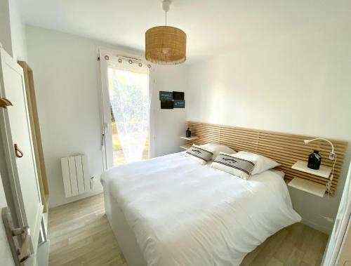 une chambre avec un grand lit blanc avec une fenêtre dans l'établissement Appartement t2 , bord de mer, accès direct plage, à Saint-Nazaire