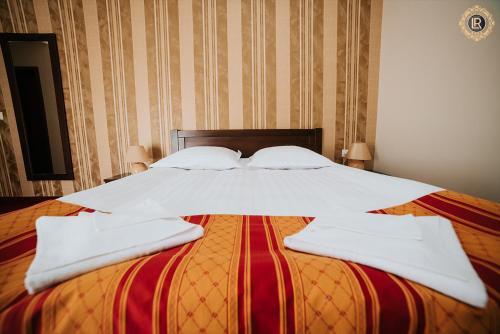 1 cama grande con sábanas blancas y almohadas. en La Rezidenta, en Sibiu