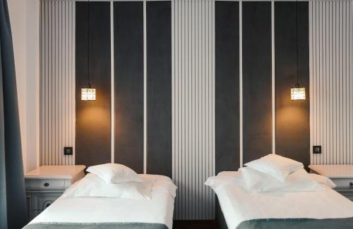 two beds in a bedroom with two lights on the wall at Hotel Eden in Iaşi