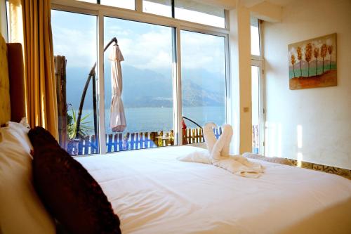 a bedroom with a bed with a large window at TIBERIAS by luxury Atitlan in San Pedro La Laguna