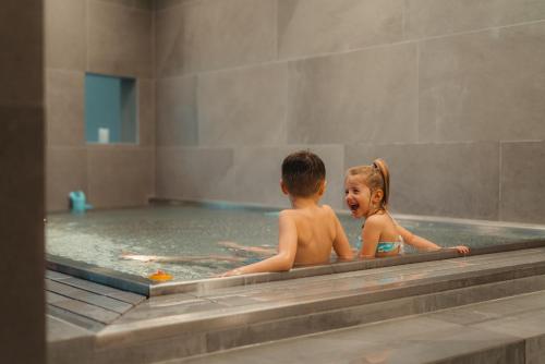 a boy and a girl in a swimming pool at Zermatt Budget Rooms in Zermatt